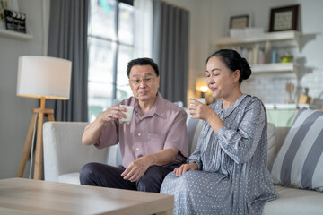 An elderly couple enjoys a peaceful moment at home, sharing smiles and drinks. The warm and cozy atmosphere emphasizes their deep connection, happiness, and the comfort of spending time together.