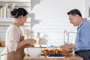 A woman prepares fresh vegetables in a cozy kitchen, while a man assists in the background. The scene emphasizes a warm and healthy lifestyle with a focus on fresh produce and home cooking.