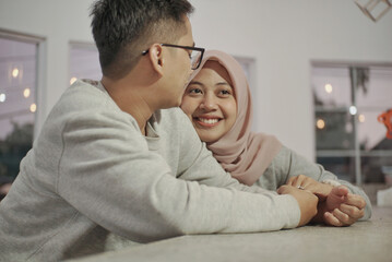 Fototapeta premium romantic Asian husband and wife sitting and joking on the living room