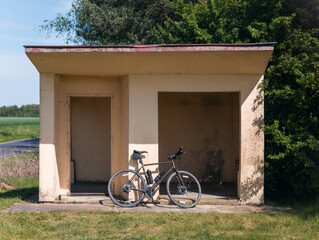 Road bicycle and an old bus stop. Summer cycling deep in the countryside of Poland
