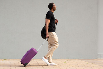 Man walking with purple suitcase on city sidewalk