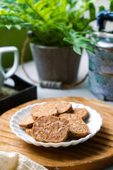A close-up view of delicious chocolate almond cookies neatly arranged on a white plate.  A popular cookies in Malaysia during Eid Mubarak (Hari Raya)