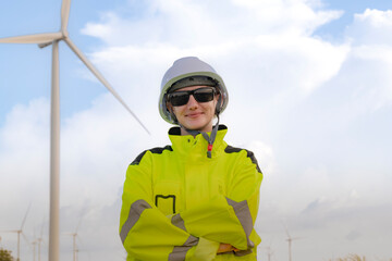 A renewable energy engineer wearing a helmet and reflective jacket, standing confidently in front of a wind turbine on a clear day, showcasing sustainable energy and modern technology