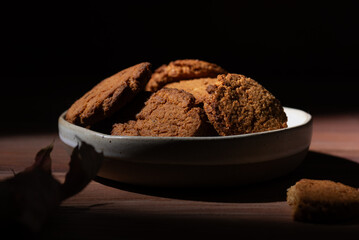 Homemade oatmeal cookies in a plate on a dark wooden table.