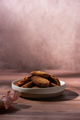 Homemade oatmeal cookies in a plate on a brown background. Vertical orientation.