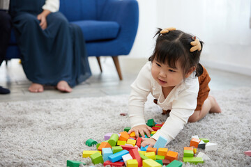 child girl feeling happy and playing with colorful toy blocks on the carpet floor