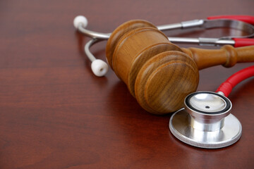 Wooden gavel and red stethoscope on wooden background. Copy space for text.