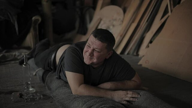 A drunk man in a dark T-shirt lies on the ground.Problems with alcoholism, alcohol addiction. baguette art workshop
