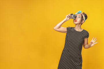 Emotional Asian girl dressed in pin-up style with vintage camera in her hands doing photo shoot on...