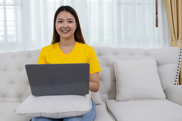 Naklejka premium Smiling Woman Using Laptop on Couch