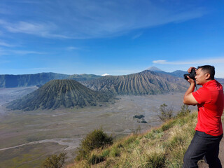 Naklejka premium A photographer aims his camera to take a picture of Mount Bromo, one of most popular volcanos in East Java, Indonesia.