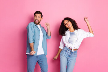 Joyful young couple dancing together against a pink backdrop showcasing connection and happiness