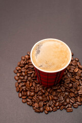 Paper cup with coffee on roasted coffee beans