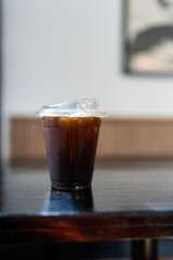 A plastic cup of iced Americano or black coffee on wood table