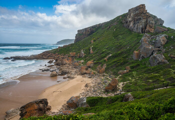 A view of the coastline with rocky mountains waves and a sandy beach at Robber nature reserve along the Garden route, Plettenberg Bay, Western Cape province, South Africa, Africa