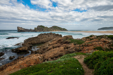 A rocky and majestic coastline with a beach and waves and pathway at Robberg nature reserve along the Garden route, Plettenberg Bay, Western Cape province, South Africa, Africa
