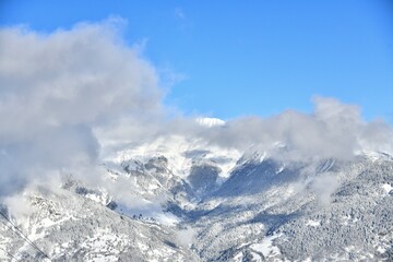 French alps on a sunny day under the clouds by winter covered with snow.