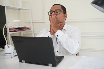 Nervous man thinking over problem trying to focus at work, young businessman sitting at workplace with laptop holding hands in concentration gesture collecting thoughts or making important decision