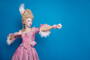 Elegant woman in vintage pink dress poses against blue background, blending historical fashion with a touch of humor and style
