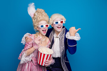 Couple in vintage costumes enjoying a playful moment with 3D glasses against a bright blue background