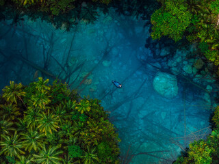 Boat in crystal blue lake with crystal water in tropics. Aerial view
