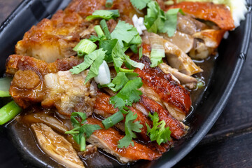 Roasted duck and crispy pork belly on dish with sauce.