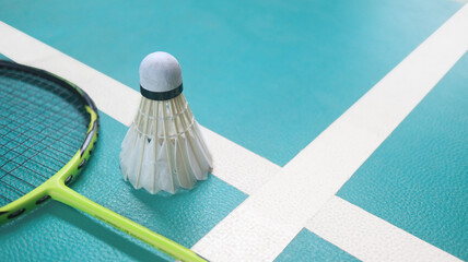 White badminton shuttlecocks and badminton rackets on green floor indoor badminton court. Concept for badminton competition and its lovers.