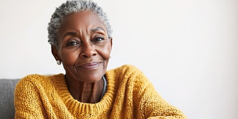 nostalgic 75-year-old african american woman wearing cozy knitted sweater sitting on chair with wistful smile gazing