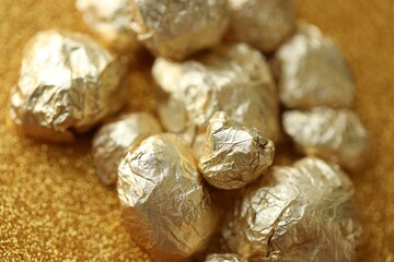 Small pile of golden nuggets on shiny gold glitter background