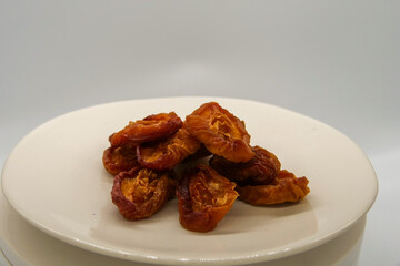 Dried nectarine fruit on a white plate in front of a white background