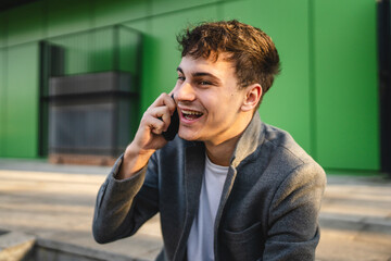 young handsome man sit on staircase and talk on mobile phone