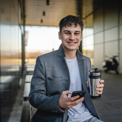 young man drink coffee sit on bench and use mobile phone on break