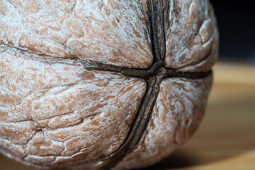 Macrophoto of a ripe walnut, the texture of the shell of a large-fruited walnut variety, ready to split. A cross on a walnut shell.