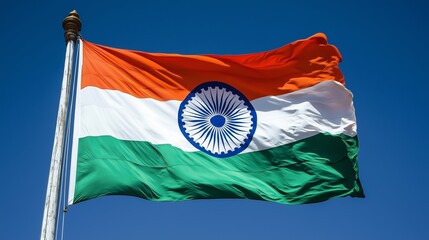 A close-up of an Indian flag waving in the wind with vibrant colors against a blue sky.