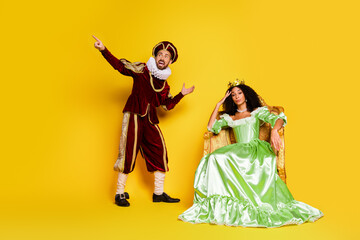 Playful Couple in Elegant Renaissance Costumes Surrounded by Vibrant Yellow Backdrop