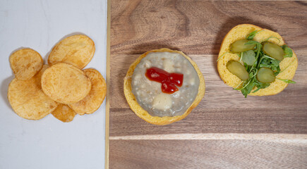 Zenithal view of a house made burger with cucumber, arugula, cheese, tomato and chips