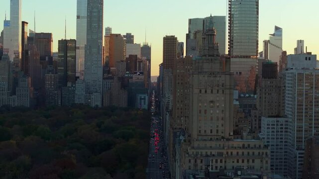 Warm sunset light envelops Midtown Manhattan's skyscrapers including The San Remo, highlighting the skyline. Cars navigate Central Park South
