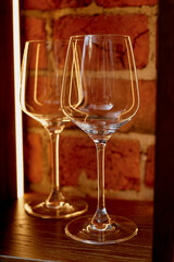 Wine glasses made of thin glass against a red brick background, with lighting. Glasses at the bar.