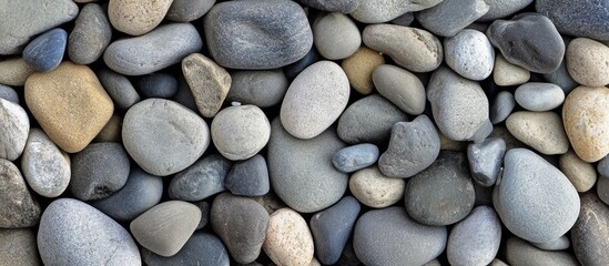 Smooth beach stones arrangement for natural texture background in shades of gray and beige ideal for design and artistic projects.
