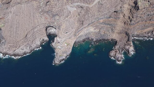 Rugged volcanic coastline merging with Atlantic waters near Poris de Candelaria. Dramatic rock formations and transparent blue seascape in La Palma, Canary Islands, Spain