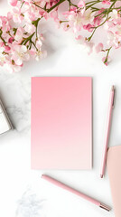 A serene workspace featuring a pink gradient notebook, pens, and blooming flowers.