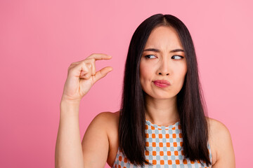 Charming young Asian woman with confused expression in stylish top on pink background