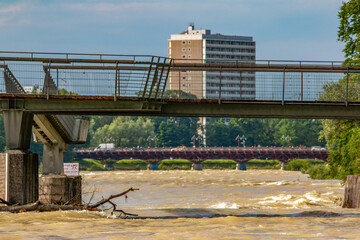 In summer, the Isar flooded in Munich. Current and driftwood in the water. View of the bridge.