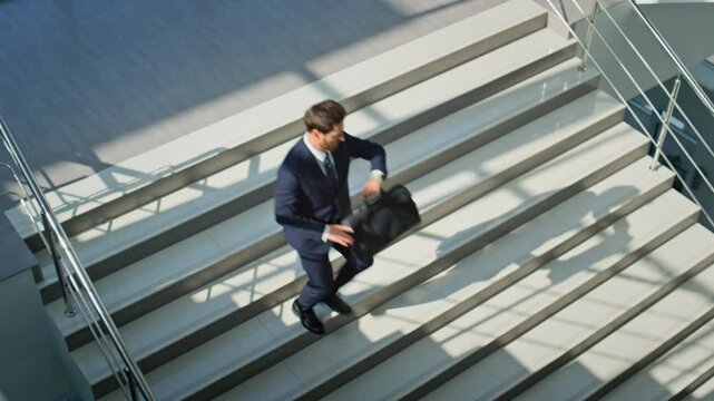 Successful worker hurrying downstairs looking wristwatch. Motivated businessman