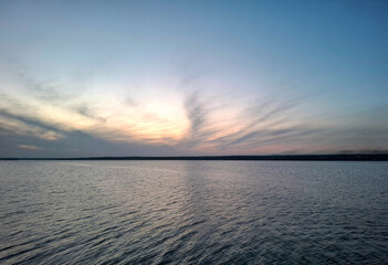 sunset on the river. dark cirrus clouds are illuminated by the setting sun and reflected on the wavy surface of the water
