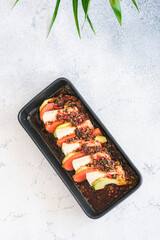 Top view of a modern dish with smoked salmon, creamy tofu, and avocado slices, finished with a spicy chili dressing.