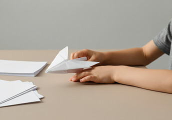 Child engages in creative paper airplane making on a table