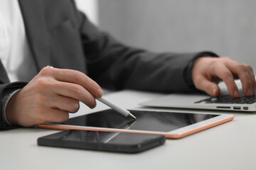 Businessman using different devices at white table indoors, closeup. Modern technology