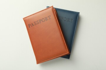 Passports in color covers on light background, top view