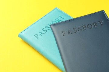 Passports in color covers on yellow background, closeup